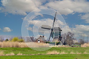 Landscape with dike and historic Oukoopse molen along the Enkele Wiericke in the Dutch province of Zuid Holland
