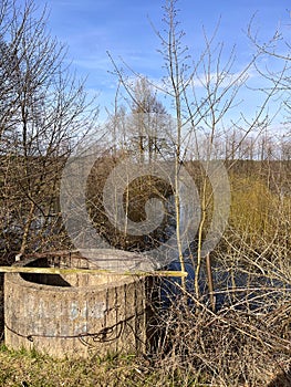 landscape in early in spring - an old abandoned well on the river bank