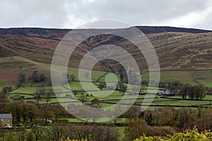 Landscape of the Edale Valley covered in greenery under a cloudy sky in the UK