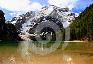 Landscape with the emerald surface of Lago di Braies lake and snowcapped mountains in the Dolomites, Italy photo