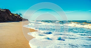 landscape empty deserted sand beach and sea waves with foam surf with blue sky and white clouds