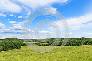 Landscape of European plains with hills and lowlands, marshes, meadows and forests. Cloudy Blue sky over horizon