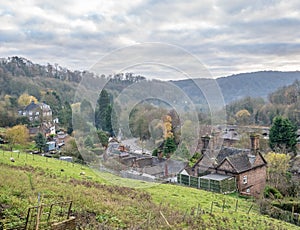 Landscape of a farm surrounded by houses and greenery under a cloudy sky in Ironbridge