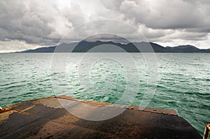 Landscape with ferry ramp, tropical sea, monsoon storm heavy clouds and tropical Koh Chang island on horizon in Thailand