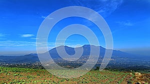 landscape of fertile land for plantations under the foot of the mountain with a blue sky in the background