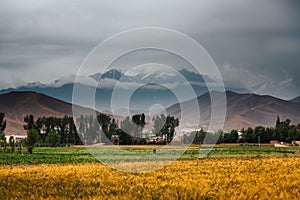 Landscape of a field surrounded by beautiful mountains under a stormy sky in Bamyan, Afghanistan