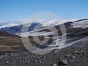 Landscape of Fimmvorduhals hiking trail. Eyjafjallajokull glacier and volcano, lava ash, blue stream from melting snow