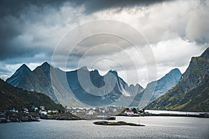 Landscape of fishing village Reine with the Reine Fjord during sunset with nice lights on mountain, blue sky and clouds
