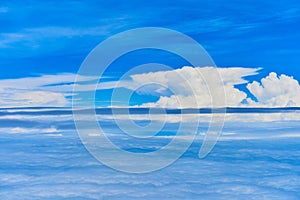 Landscape of fluffy white clouds on a dark blue sky. View from the plane at high altitude