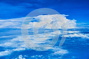 Landscape of fluffy white clouds on a dark blue sky. View from the plane at high altitude