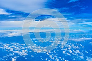 Landscape of fluffy white clouds on a dark blue sky. View from the plane at high altitude