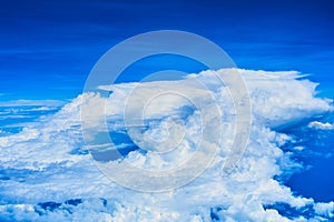 Landscape of fluffy white clouds on a dark blue sky. View from the plane at high altitude