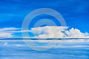 Landscape of fluffy white clouds on a dark blue sky. View from the plane at high altitude