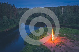 Landscape of forest and river at night. Huge fire. Midsummer.