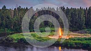 Landscape of forest and river at night. Huge fire. Midsummer.