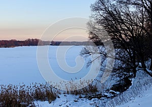 Landscape with a frozen river at sunset in winter