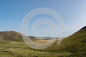 Landscape of the grassland surrounded with hills under the clear sky