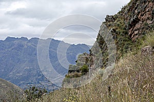 Landscape with green Andean Mountains and Inca ruins on the hiking path in Pisac archeological park, Peru