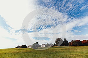 Landscape of green fields, private houses in distance, beautiful clouds in sky