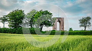 Landscape of green grass field, trees and tower.