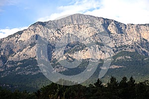 Landscape with high impregnable mountains with rocky vegetation on the slopes under blue cloudless sky on bright sunny day front v