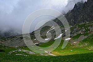 Landscape of the High Tatra mountains. Hikers on a track above Lake Velicke pleso and waterfall Velicky vodopad. Slovakia