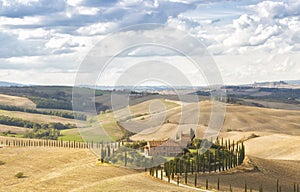 Landscape of hills, country road, cypresses trees and rural houses