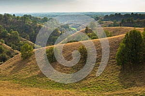 Landscape of hills covered with dry yellow grass at sunny autumn afternoon