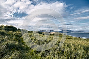 Landscape of hills covered in the grass surrounded by the Rossbeigh Strand and the sea in Ireland