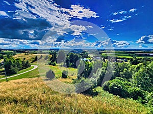 Landscape with hills and dandelion meadow. Summer mountains landscape. Meadows, ravines, thickets, open deciduous or mixed forest