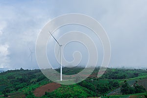 landscape of hills and wind turbines with misty foggy in morning time