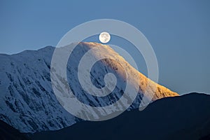 Landscape in Himalayas, Annapurna region, Nepal. Full moon during a sunrise on the background of snow-capped mountains