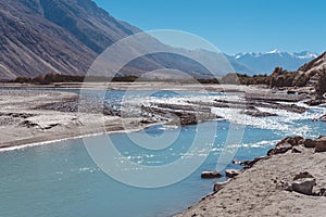 Landscape image of the blue Shyok river on the way to Nubra valley with mountain and blue sky background