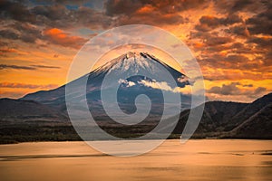 Landscape image of Mt. Fuji over Lake Motosu with autumn foliage at sunset in Yamanashi, Japan