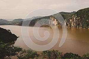 Landscape including calm brown water of Lake Nyos, famous for CO2 eruption with many deaths, Ring Road, Cameroon