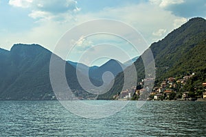 Landscape Lake Como, the silhouettes of the alpine hills above it and the cloudy sky.