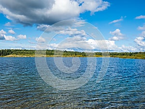 Landscape of lake and forest in the far and texture of crystal clear light Blue and green transparent water with fine white sand