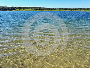 Landscape of lake and forest in the far and texture of crystal clear light Blue, green and turquoise transparent water with fine