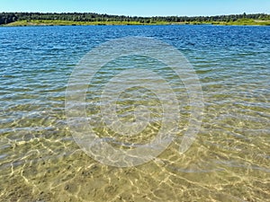 Landscape of lake and forest in the far and texture of crystal clear light Blue, green and turquoise transparent water with fine