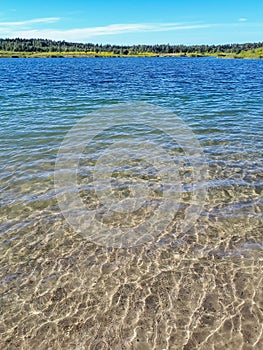 Landscape of lake and forest in the far and texture of crystal clear light Blue, green and turquoise transparent water with fine