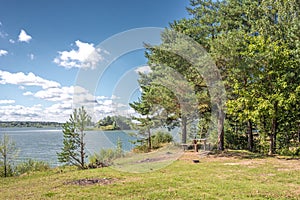 Landscape by the lake in the forest with a wooden table/Lake in the forest with a picnic table. On a sunny day