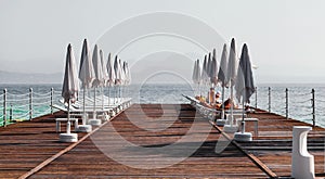 Landscape Lake Garda with pier, beach chairs and umbrellas in the foreground, Italy