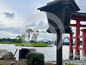 Landscape of a lake surrounded by trees, with a pillar nearby of Chinese origin