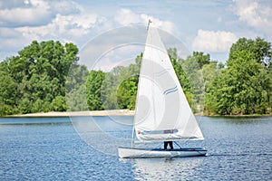 Landscape of lake with white yacht on bright sunny summer day. Blue sky with white clouds over big lakes and green trees and hills