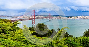 Landscape of Lisbon, Portugal skyline and the 25th of April bridge over the Tagus river estuary as seen from the hills of Almada