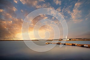 Landscape long exposure of lighthouse and jetty during Summer sunset