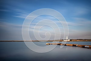 Landscape long exposure of lighthouse and jetty during Summer sunset