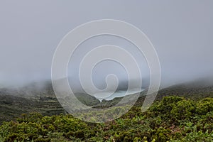 Landscape of low clouds and bad weather over Lagoa Funda das Lajes caldera volcanic crater lake at Ilha das Flores island in the photo