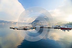 The landscape of Lugano lake in sunset twilight with clouds and blue sky.Habor and boats in Switzerland.