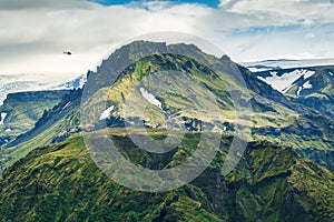 Landscape of lush rugged volcanic mountain with helicopter flying in Icelandic highlands on summer at Thorsmork